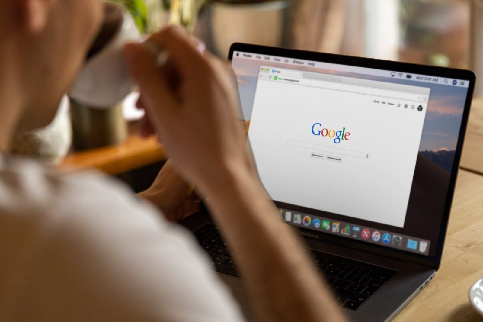 person searching on Google and drinking coffee