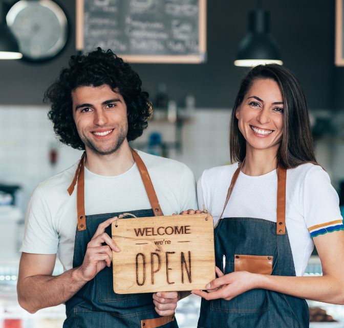 small business owners holding an "open" sign
